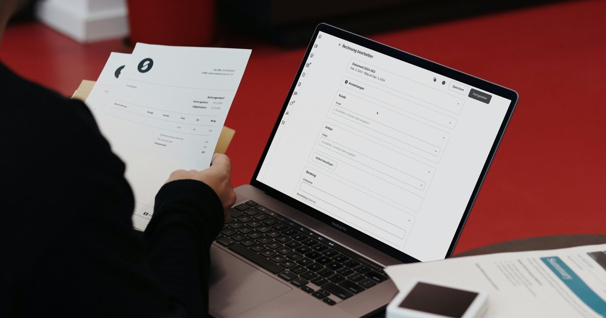 Person reviewing an invoice next to a laptop